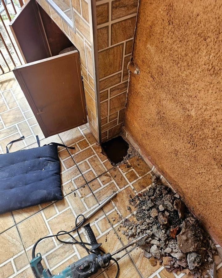Abertura pequena e pontual feita no piso para chegar ao vazamento, com o restante da cerâmica intacta e a ferramenta de corte ao lado