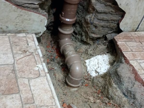 Piso cerâmico aberto apenas no ponto do vazamento, com a tubulação reparada e o restante do piso preservado